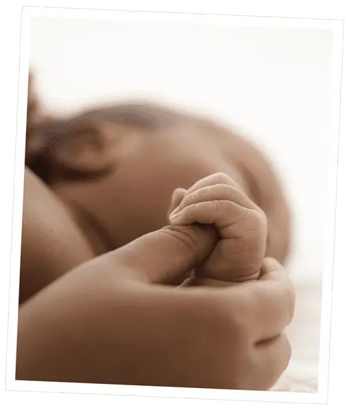 Photo of a baby's hand holding an adult's thumb